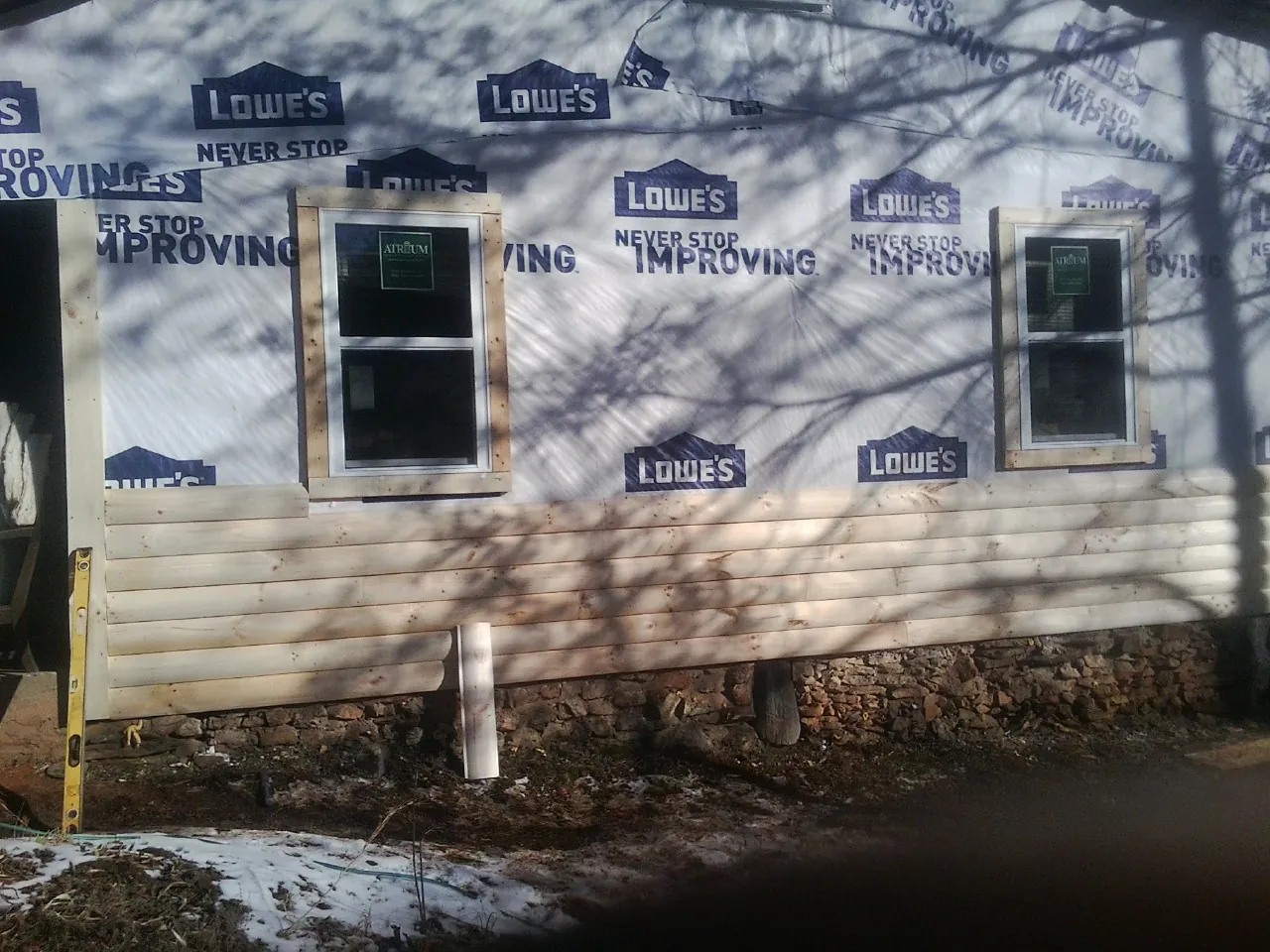 House wrap and new log siding going up on an exterior wall in White Oak