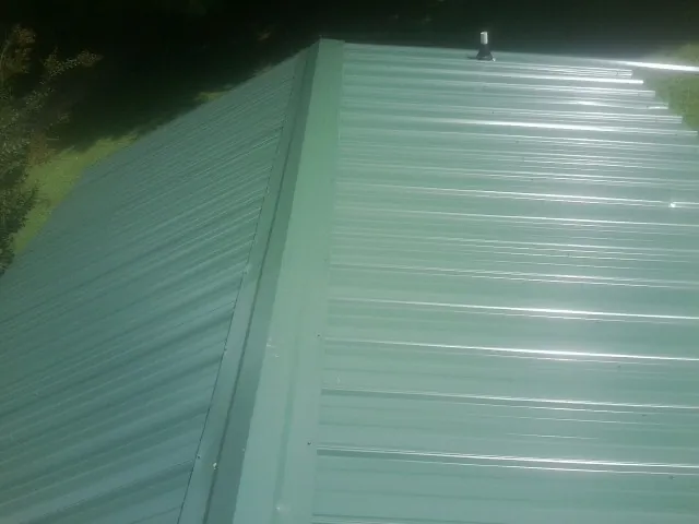 New green metal panels meeting at the ridge of a roof — Flat Roof Repair work by our crew in White Oak