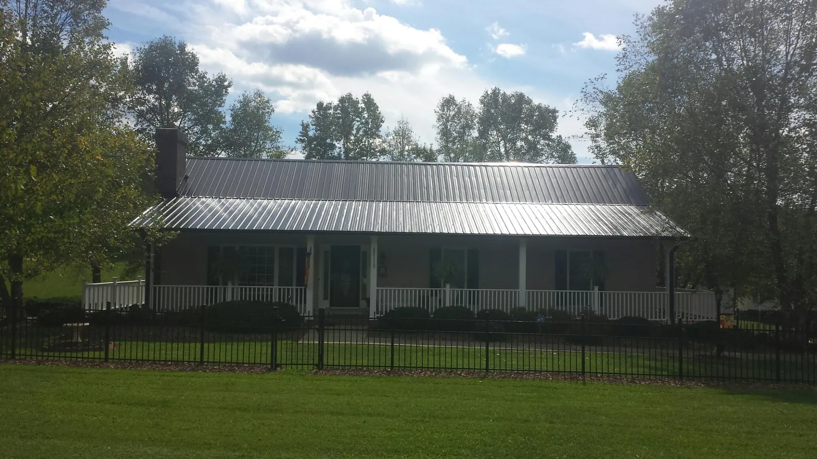 Gray metal roof on a brick ranch with a full width front porch — Gutter Guard Installation work by our crew in White Oak