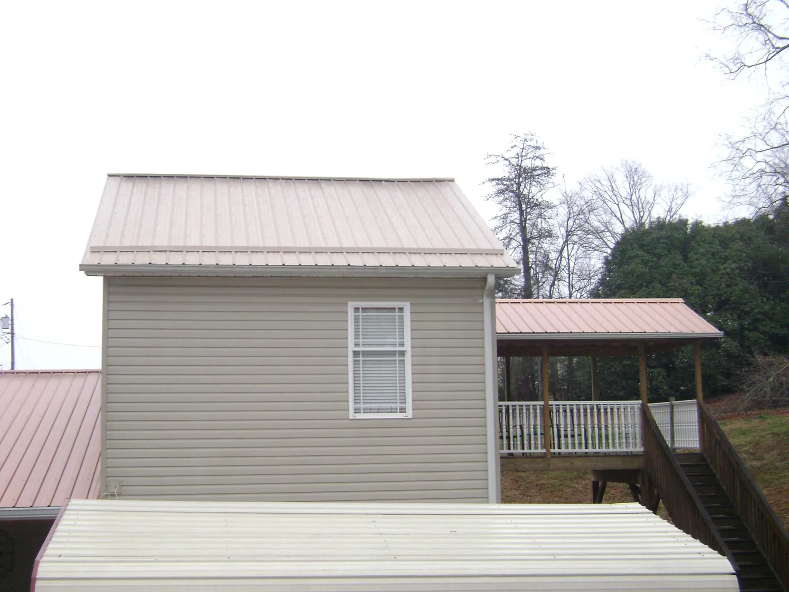 Tan metal roofs on a two story addition and attached porch, from a Roof Replacement job in White Oak