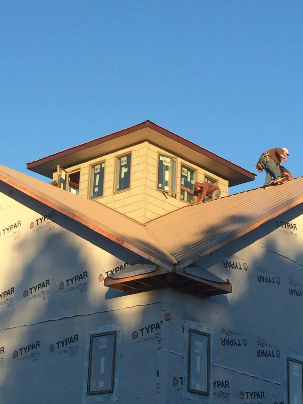 Roofers working around a rooftop cupola on a new metal roof at sunset — Roof Waterproofing in White Oak by Roofing Brothers